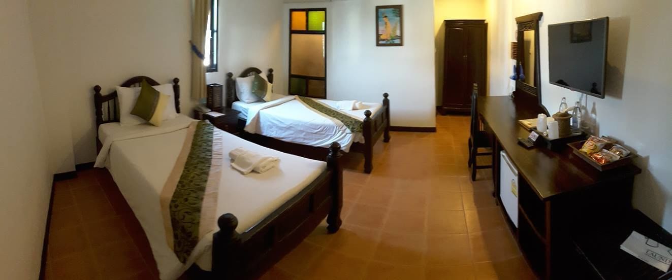 A hotel room with two single beds, a wooden dresser, a television, and a desk with a chair.