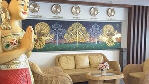 A room with a sofa, two armchairs, a decorative statue, and a wall clock. - Wangburapa Grand Hotel (Chiang Mai)