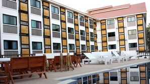 A modern hotel with a pool area, outdoor seating, and a reflection pool. - Wangburapa Grand Hotel (Chiang Mai)