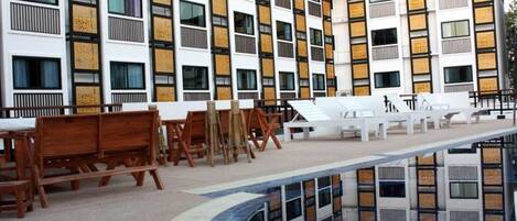 A modern hotel with a pool area, outdoor seating, and a reflection pool.