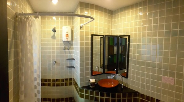 Un baño con ducha, lavamanos y espejo.