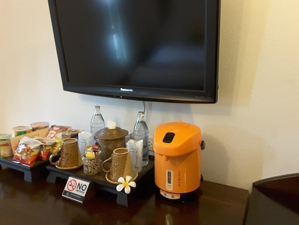 A coffee station with a no smoking sign, a Panasonic TV, and various coffee mugs and containers. - Wangburapa Grand Hotel (Chiang Mai)