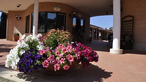 A building with a reception area, large windows, and a covered entrance with columns. - Villaggio Mare Si (Follonica)