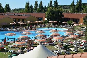 A pool area with multiple umbrellas and lounge chairs. - Villaggio Mare Si (Follonica)