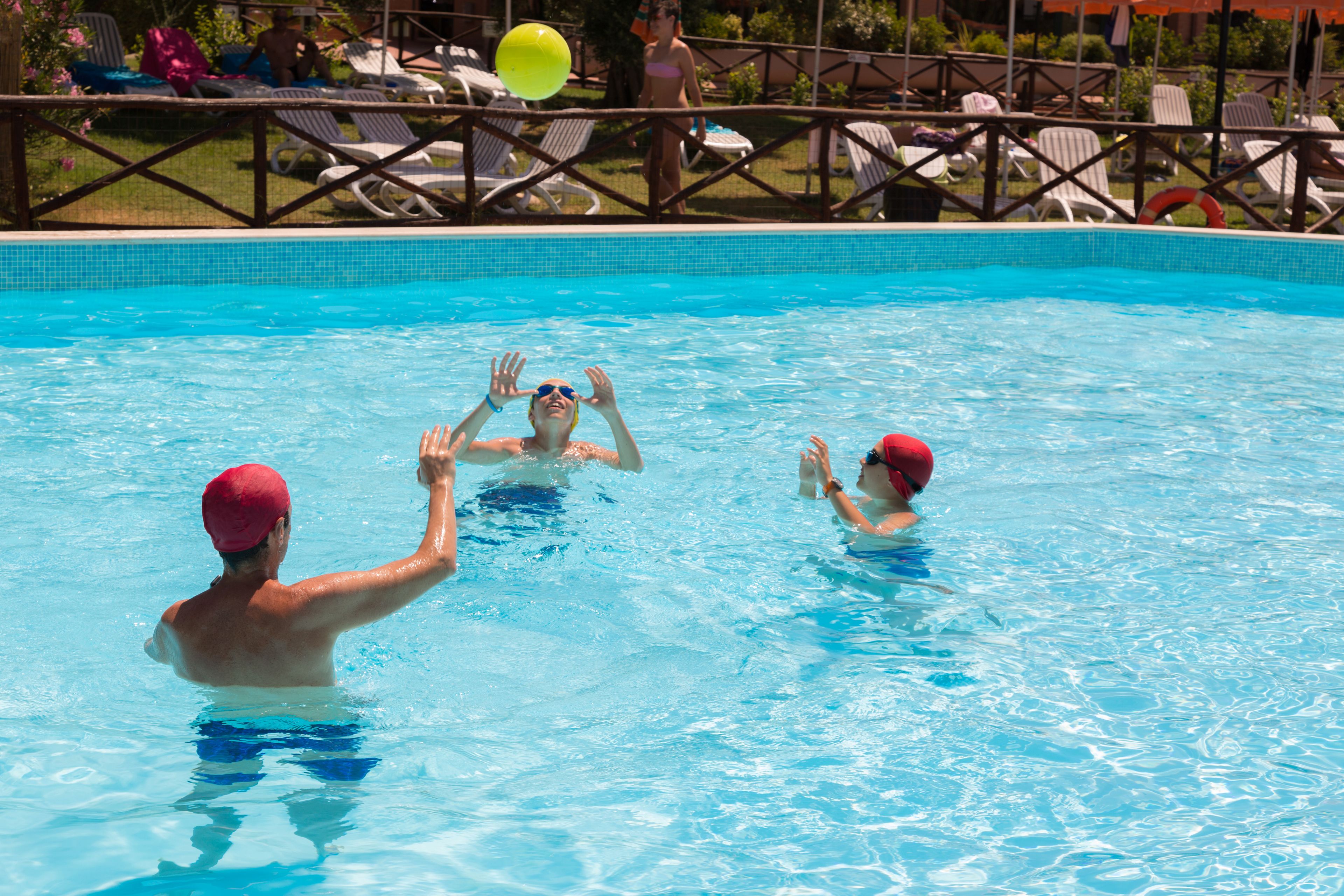 A swimming pool with people playing with a ball.