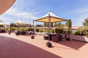 An outdoor patio area with multiple seating arrangements and umbrellas providing shade. - Villaggio Mare Si (Follonica)