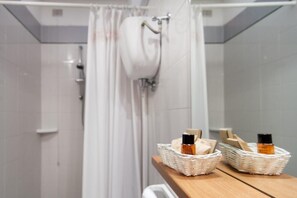 A bathroom with a shower curtain, two wicker baskets on a shelf, and a white towel hanging on a rack. - Villaggio Mare Si (Follonica)