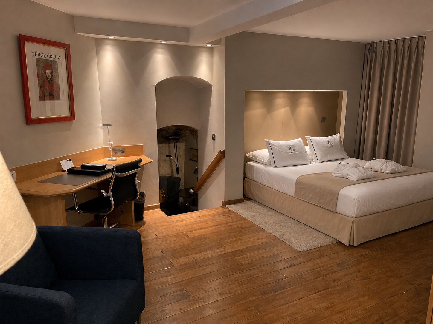 Ein Hotelzimmer mit Bett, Schreibtisch, Stuhl und einer Treppe.