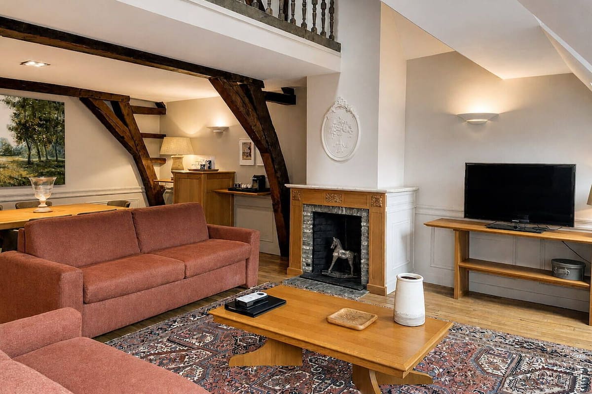 A living room with a fireplace, a sofa, a coffee table, a television, and a staircase.