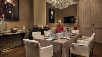 Un comedor formal con una larga mesa, sillas blancas tapizadas, una araña y obras de arte en las paredes.