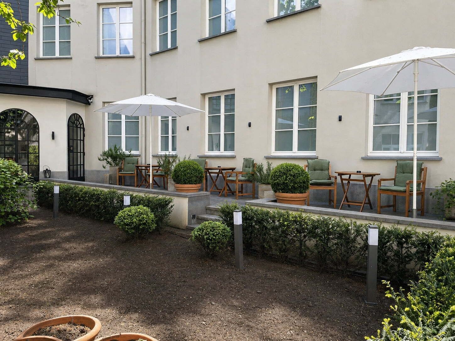 Un bâtiment doté d’un patio comprenant un espace extérieur aménagé avec des sièges et des plantes en pot.