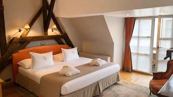 Une chambre à coucher avec un lit, des oreillers, une table de chevet, une chaise et une fenêtre avec des rideaux.