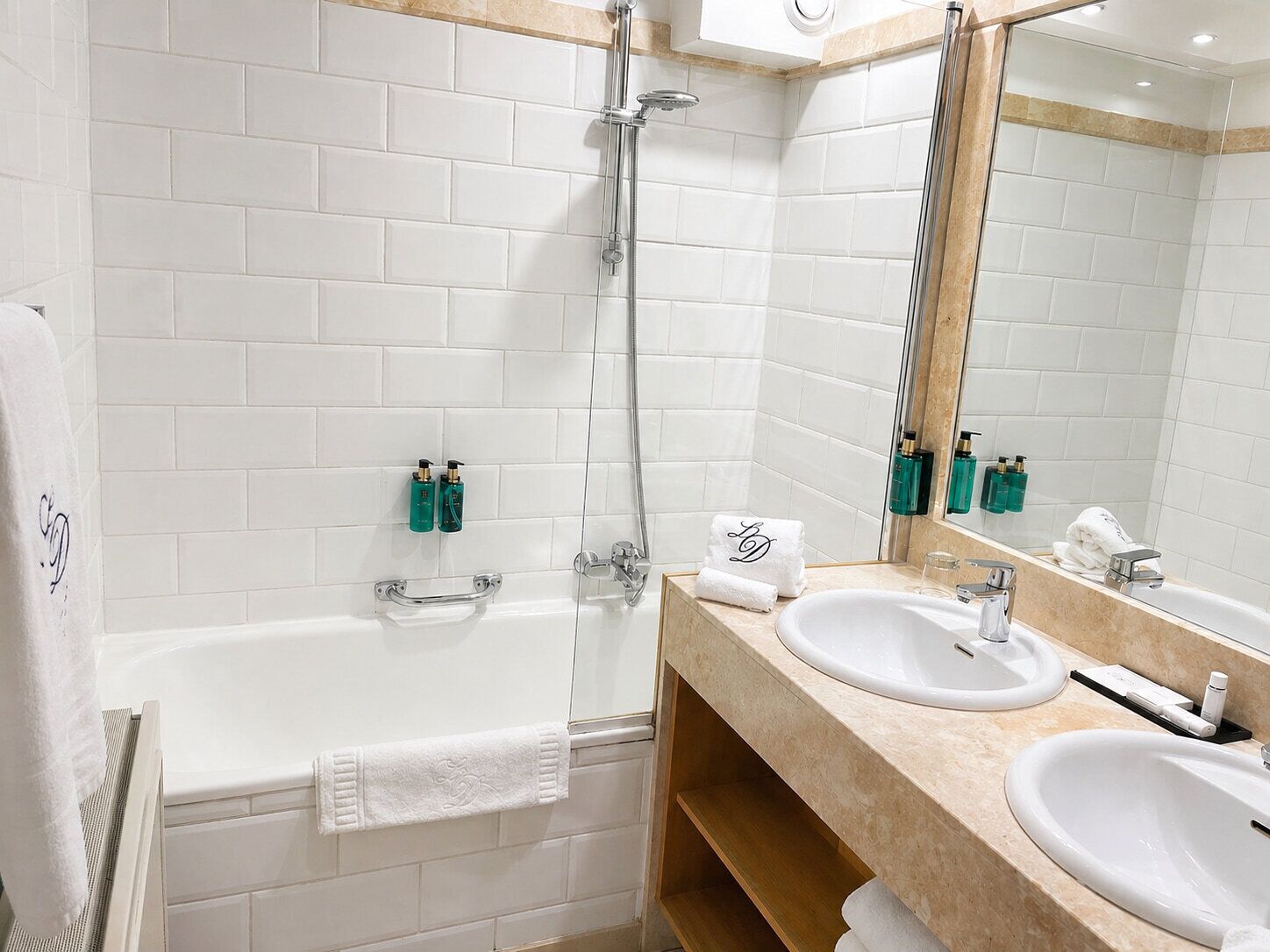 Un baño moderno con bañera, dos lavamanos y un espejo grande.