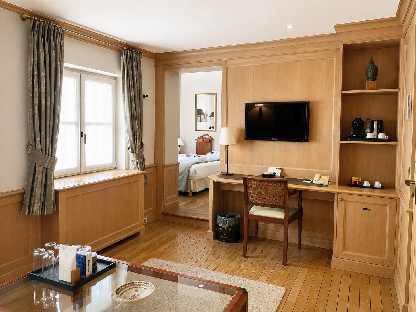 A hotel room with a bed, desk, chair, television, and a small bathroom.