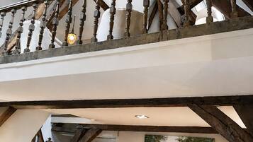 A room with a high ceiling, exposed wooden beams, a dining table with chairs, and a painting on the wall.