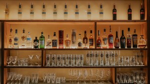 Un bar con varias estanterías llenas de botellas de licores y vasos.