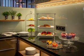 Disposição de buffet com diversos alimentos e uma seleção de frutas.