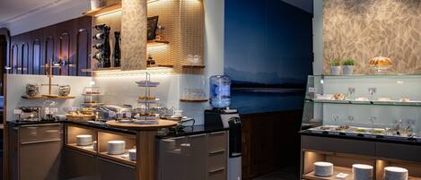A modern kitchen with a central island, built-in wine racks, and a scenic wall mural.