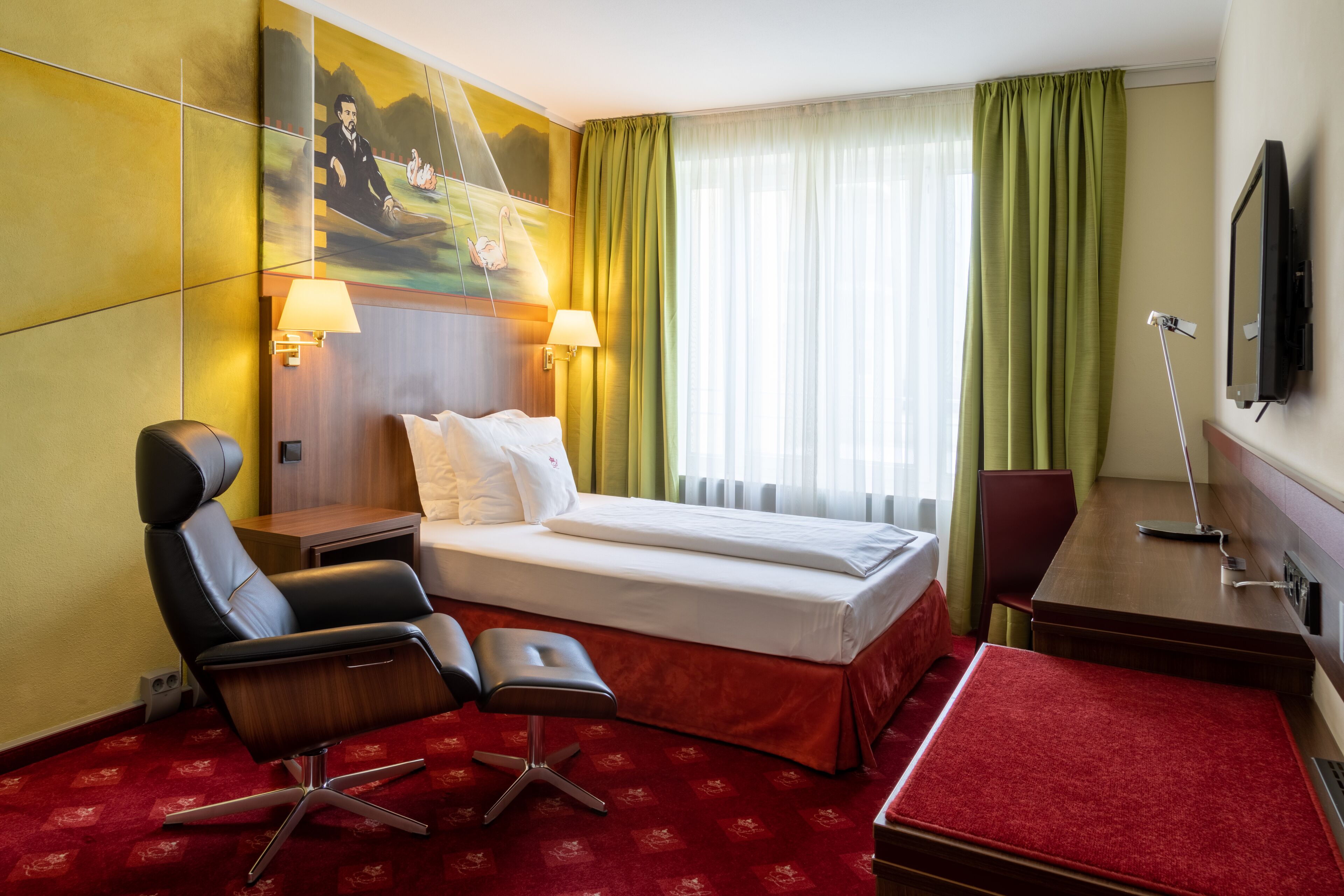 A hotel room with a bed, two bedside lamps, a desk with a chair, a television, and a painting on the wall.