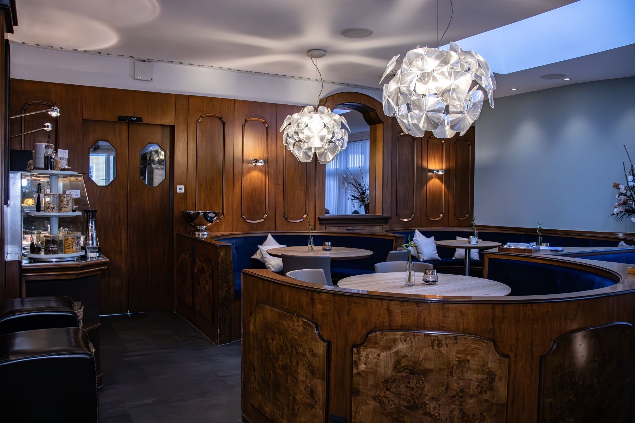 Ein Restaurant mit Holzwandverkleidung, runden Tischen und einer zentralen Bar.