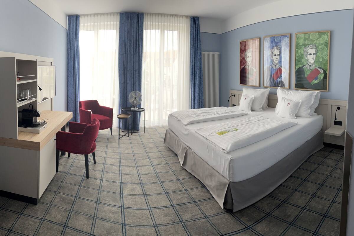 Una habitación de hotel con cama, escritorio, silla, armario y ventana con cortinas.