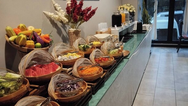 A buffet with various food items and a vase of flowers. - WE Valley Hotel (Chiang Mai)