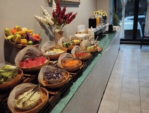 A buffet with various food items and a vase of flowers.
