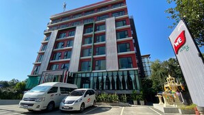 A multi-story building with a red and white facade, large windows, and a sign with "WE" on it. - WE Valley Hotel (Chiang Mai)