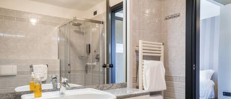 A modern bathroom with a large mirror, a sink, and a shower.