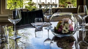 A dining table with wine glasses and a floral centerpiece, set against a view of a large building and trees. - Hotel La Casa del Mulino (Merone)