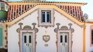 Un bâtiment doté de détails architecturaux raffinés, de deux portes symétriques et d’une petite table entourée de chaises.