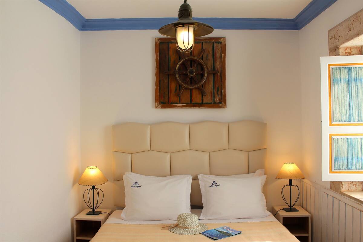 Ein Schlafzimmer mit einem großen Bett, zwei Nachttischlampen, einem dekorativen Wandbild und einem gerahmten Bild an der Wand.