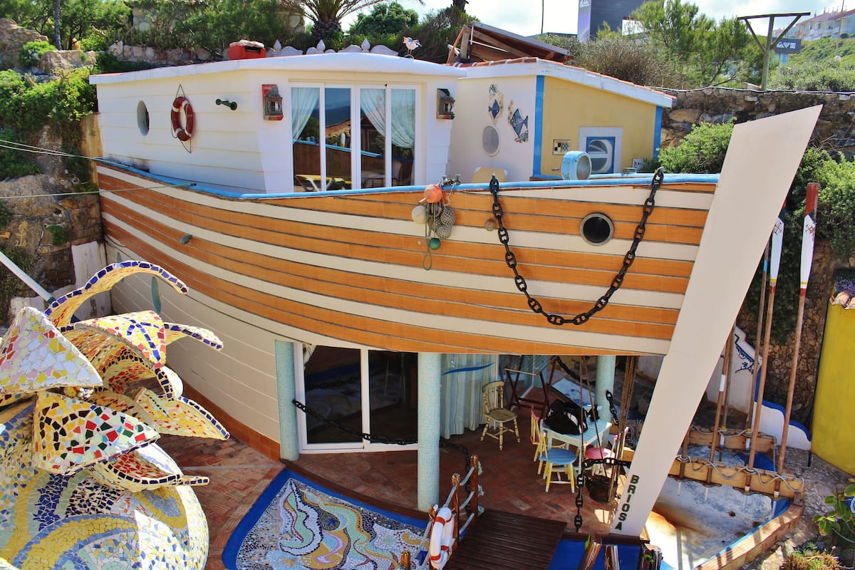 Ein Hausboot mit überdachter Terrasse, Essbereich und kleiner Sitzecke außen.