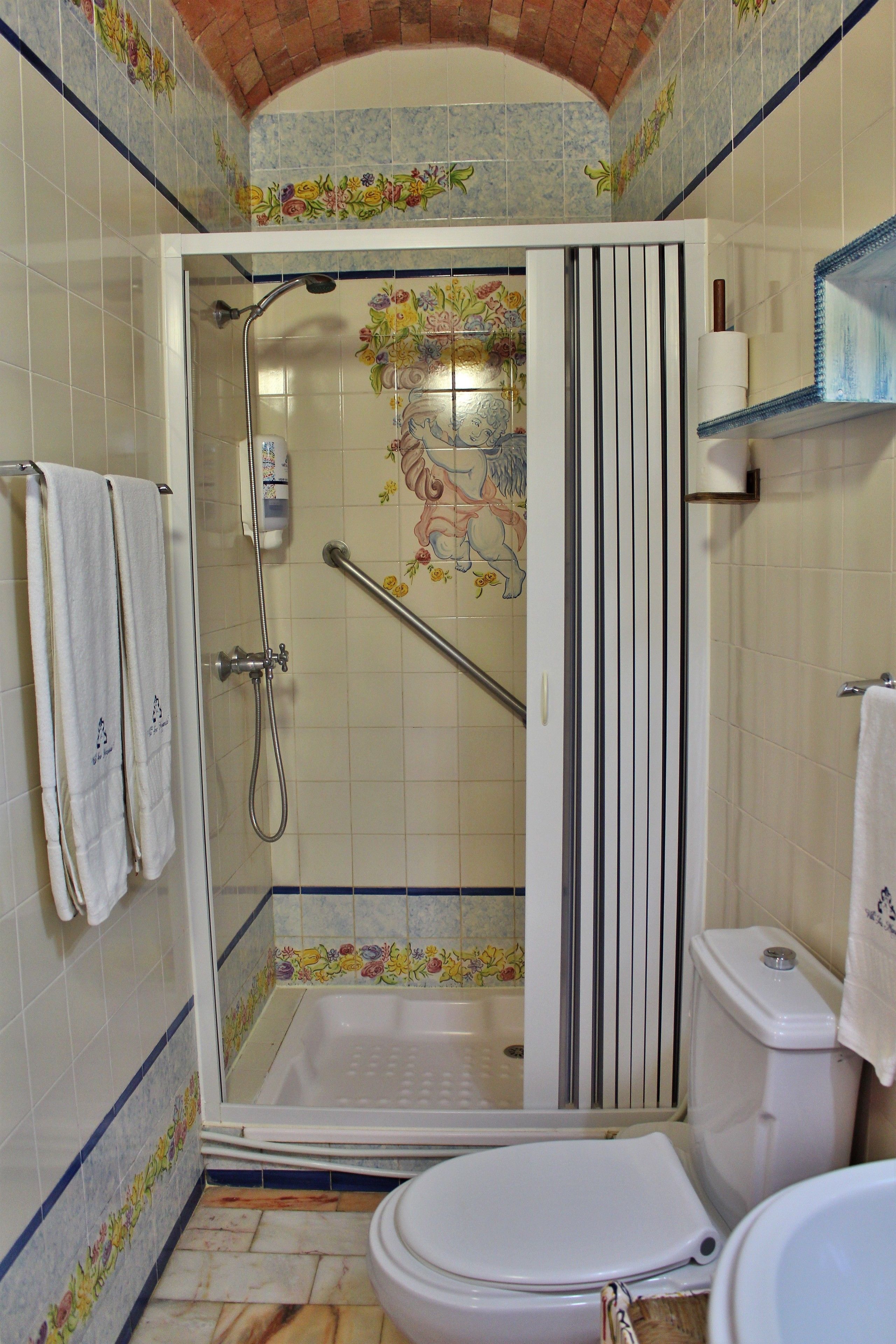 Un bagno con doccia, servizi igienici e una parete decorata con piastrelle.