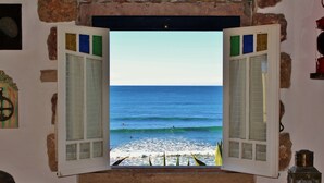 Une chambre avec vue sur la mer, les volets étant ouverts.