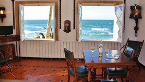 Un espace repas avec vue sur l’océan, des meubles en bois et une table avec des verres à vin.
