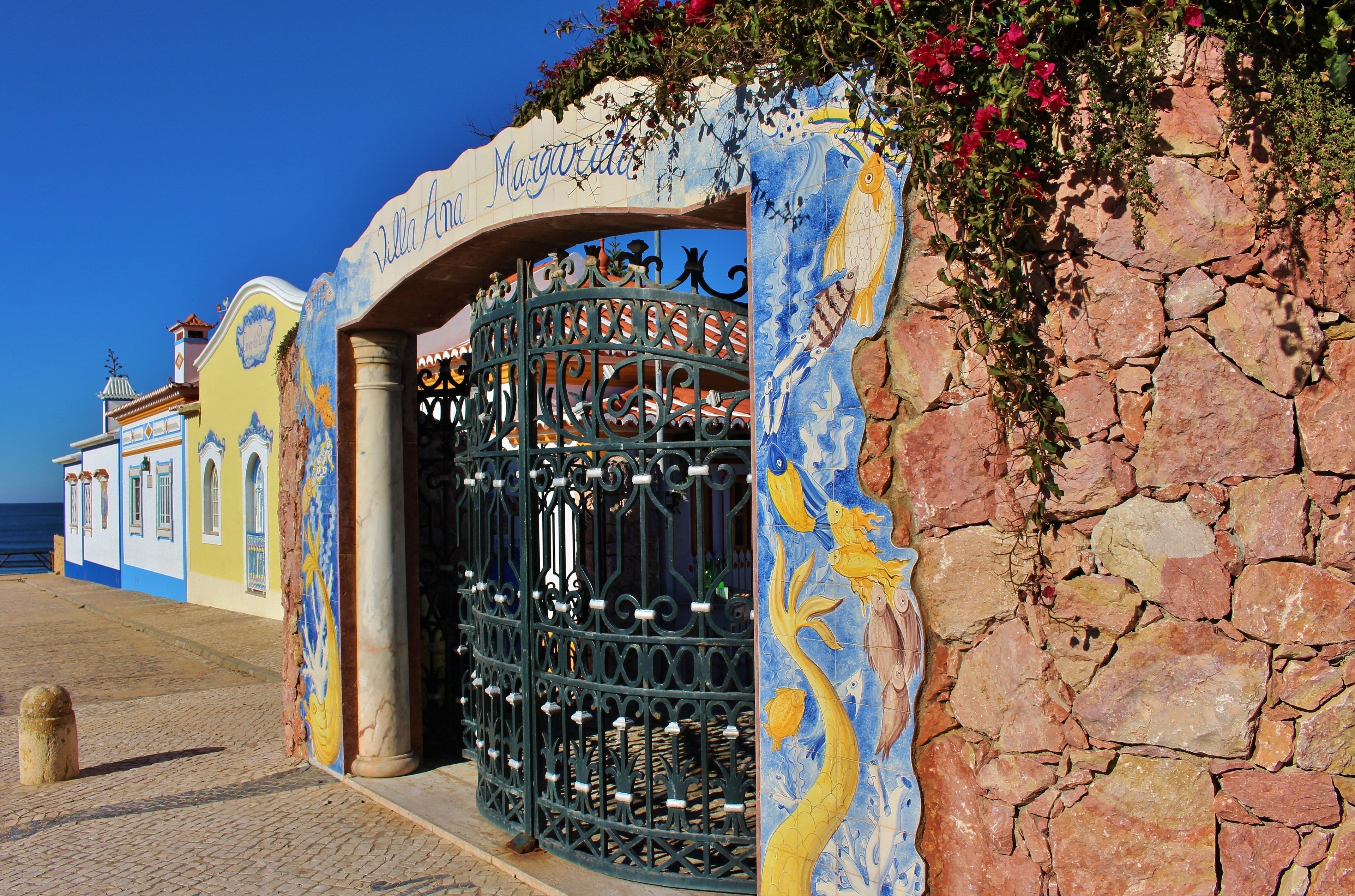 A colorful building with a stone wall and a metal gate.
