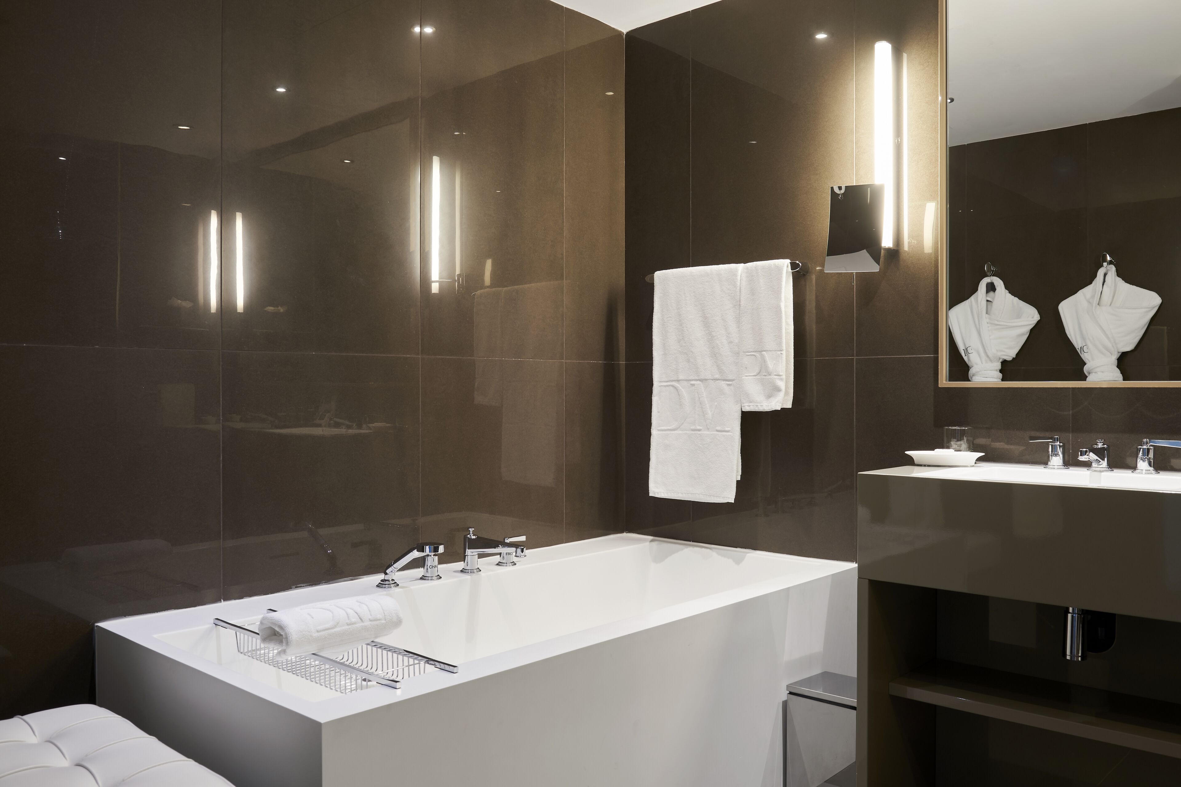 A modern bathroom with a large bathtub, a mirror, and two sinks.