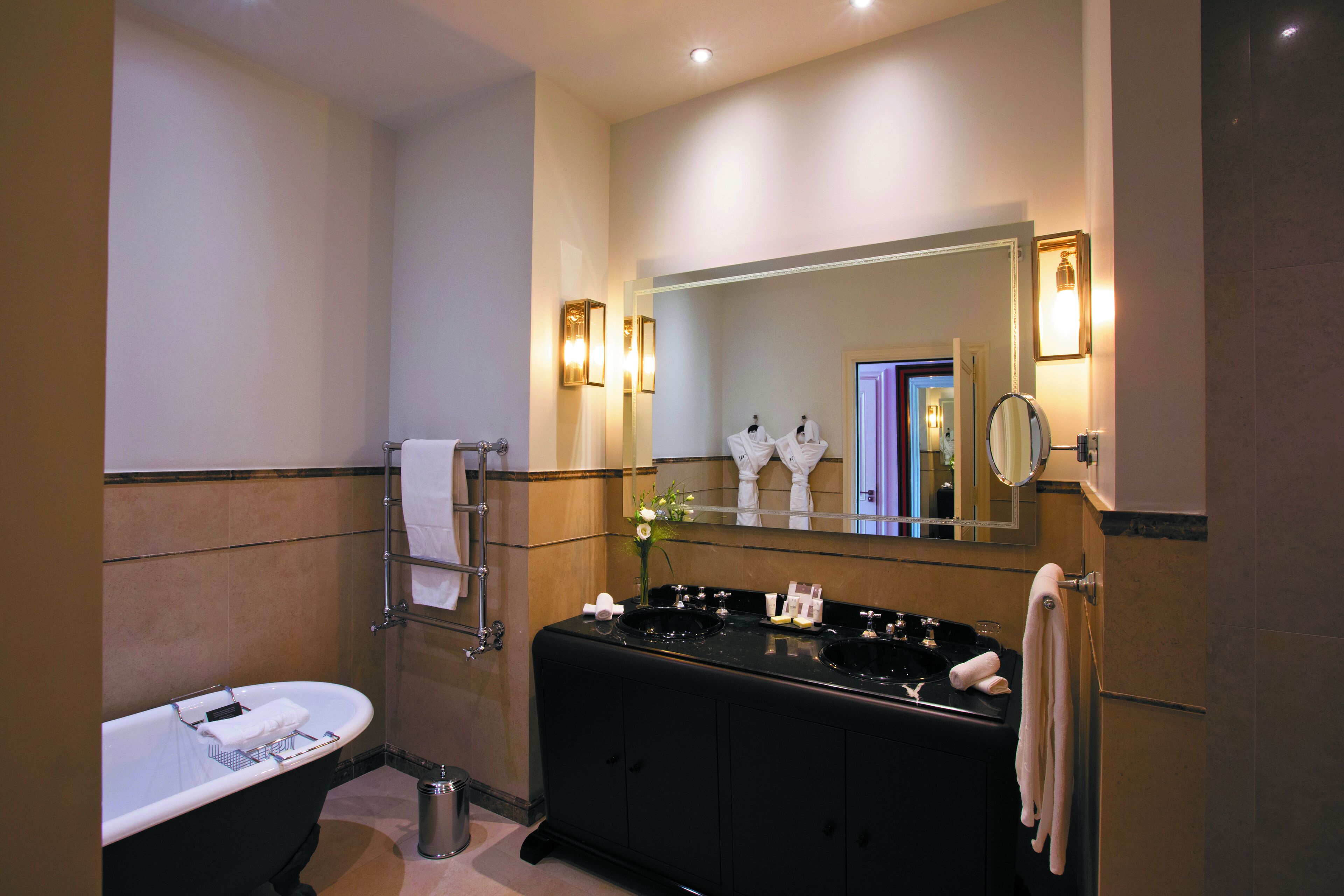 A modern bathroom with a freestanding bathtub, a vanity with two sinks, and a large mirror.