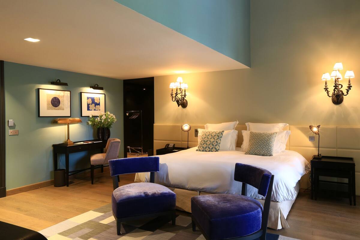 A hotel room with a bed, two chairs, a desk, and a nightstand.