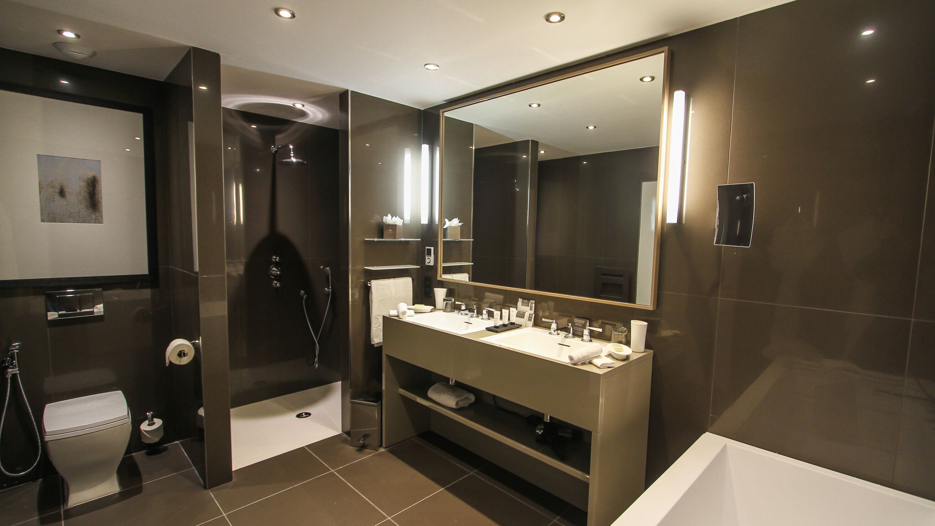 Un bagno moderno con un ampio specchio, due lavabi, una doccia e un WC.