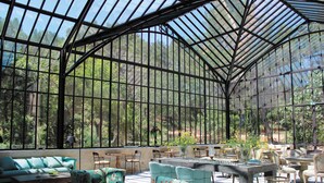 A conservatory with a glass roof, seating areas, and a central table. - Domaine de Manville (Les Baux-de-Provence)