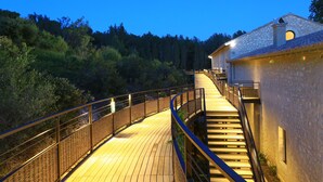 Un pont en bois mène à un bâtiment en pierre doté d’un escalier.