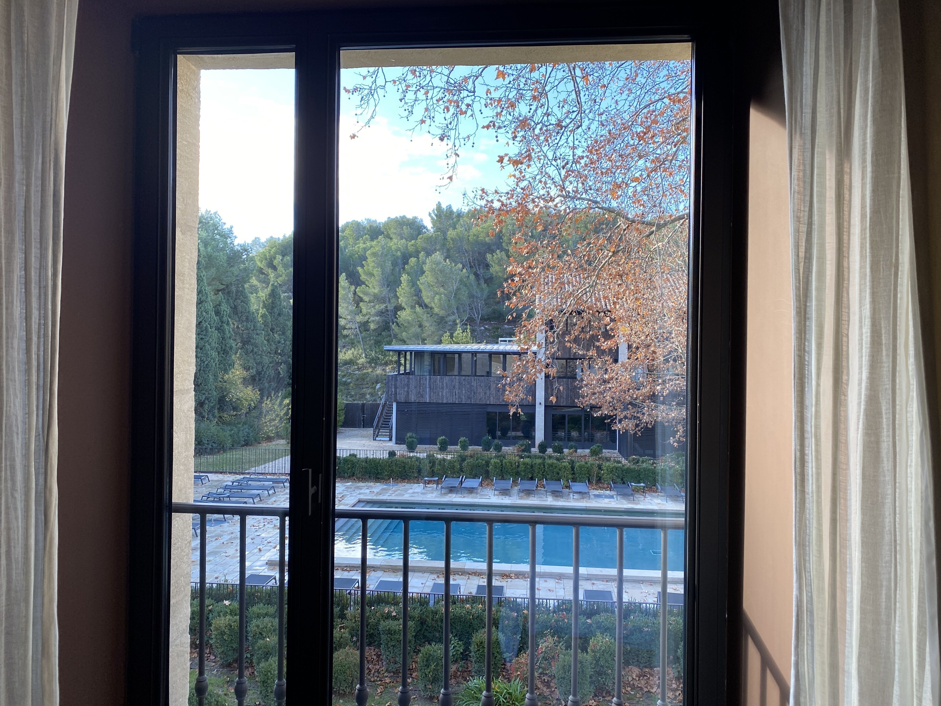 A modern building with a pool and solar panels, surrounded by trees and a clear sky.