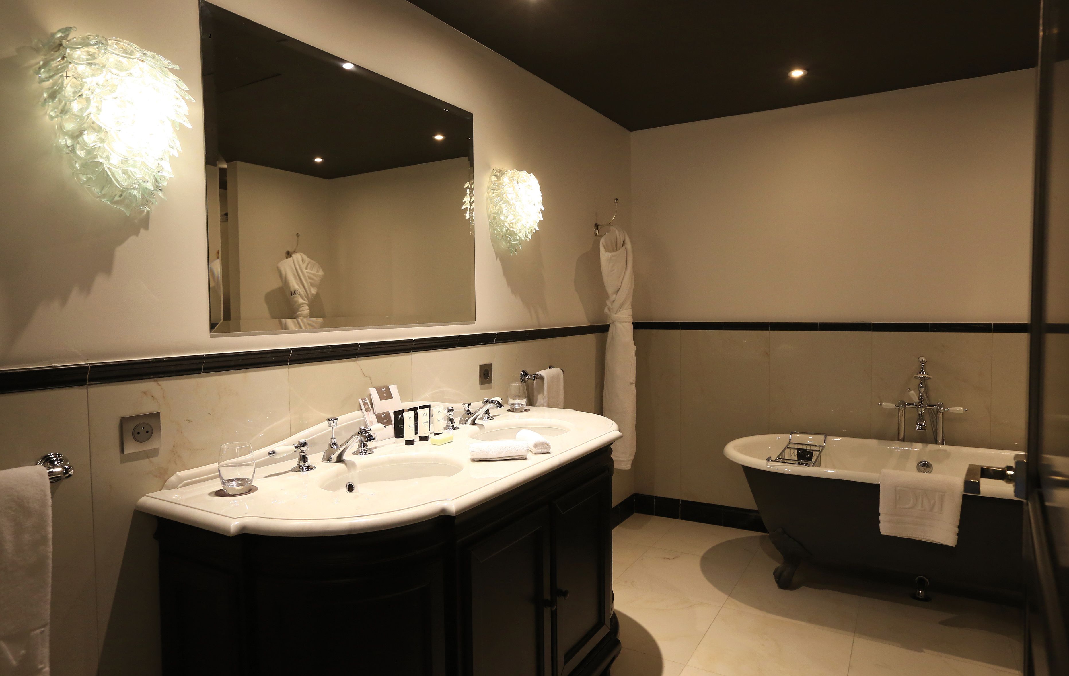 Ein modernes Badezimmer mit einem Doppelwaschbecken, einer freistehenden Badewanne und einem großen Spiegel.