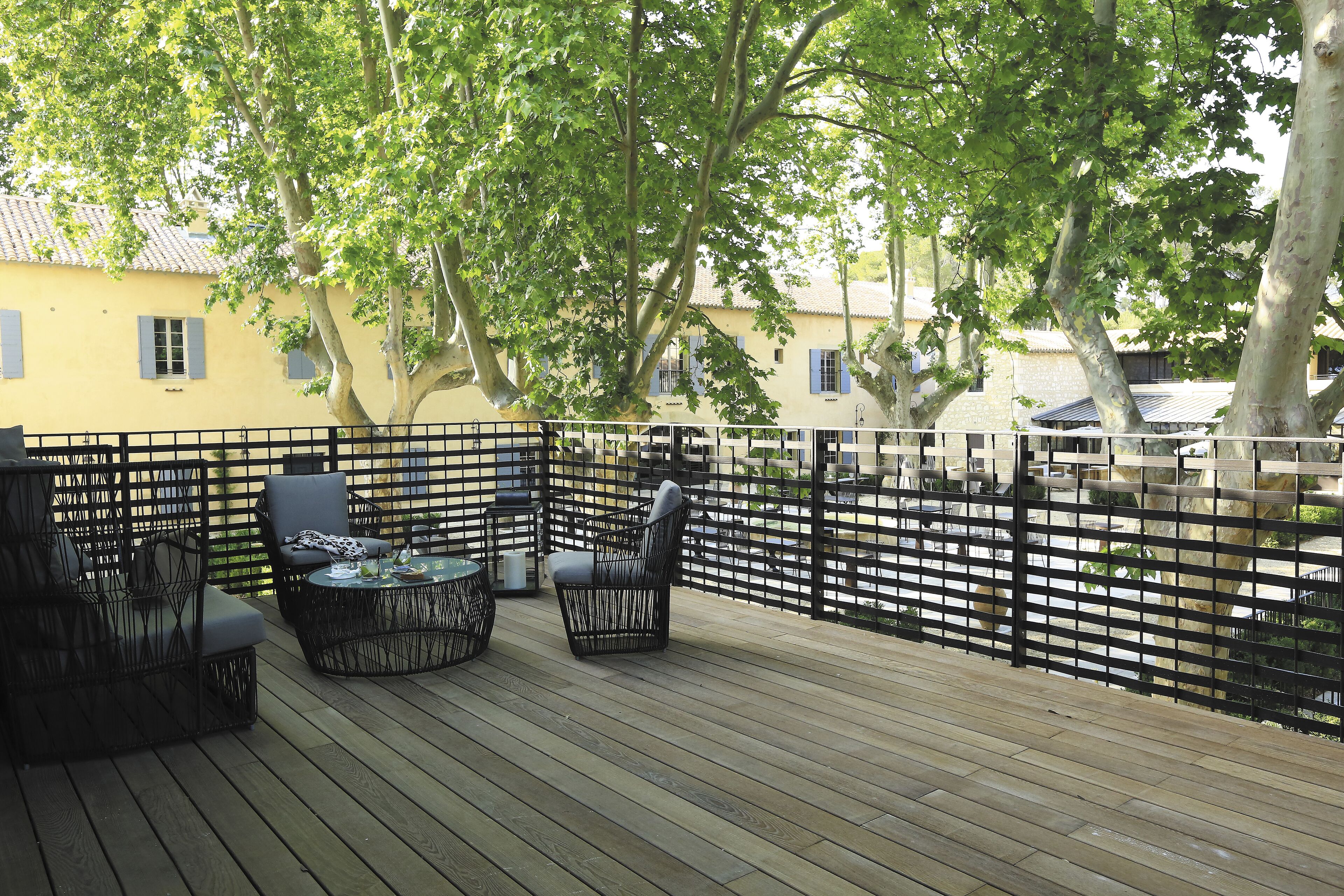 An outdoor deck with wicker furniture and a black fence.
