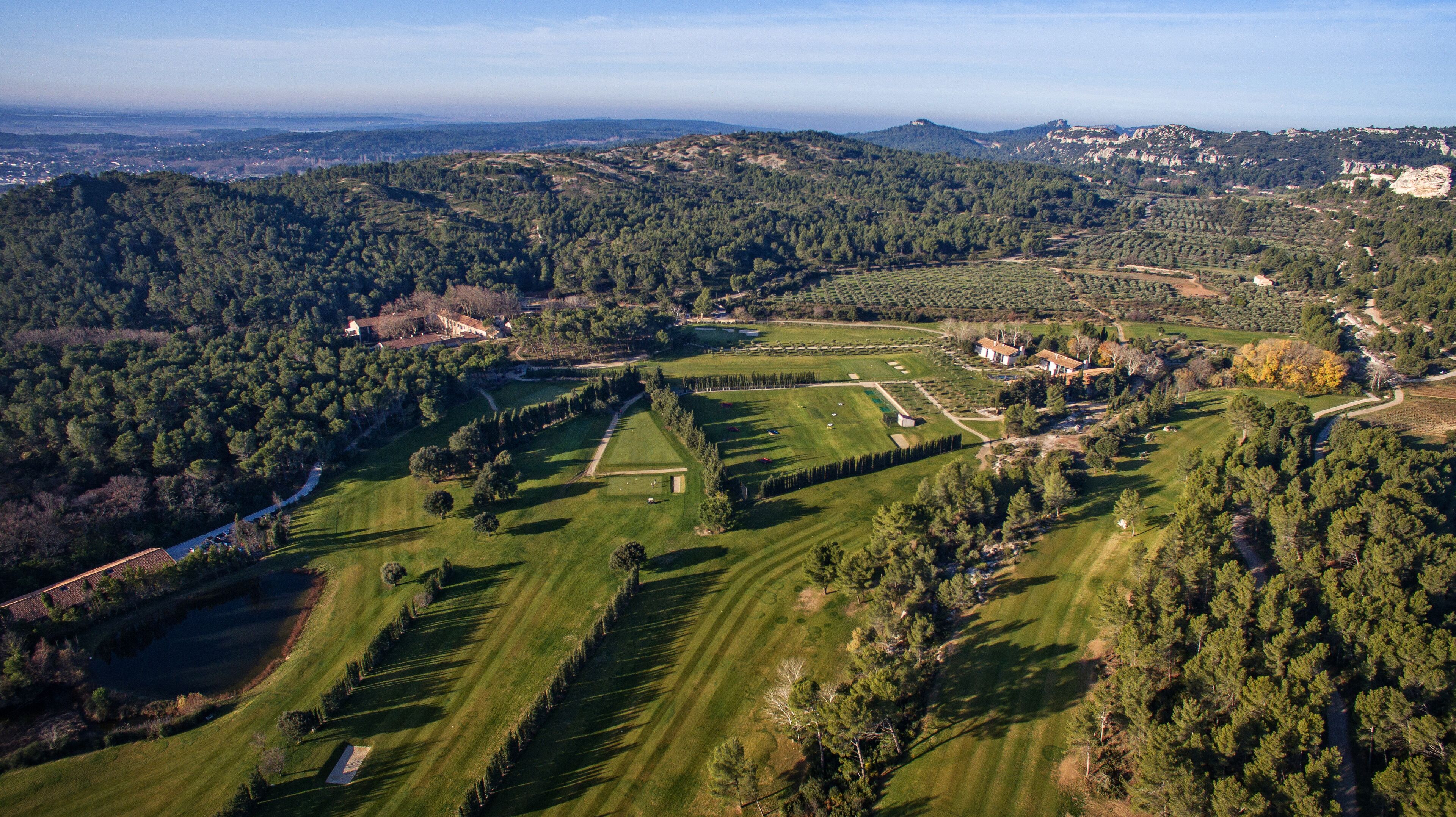 An aerial view of a large estate with expansive green lawns, a variety of trees, and a few buildings.