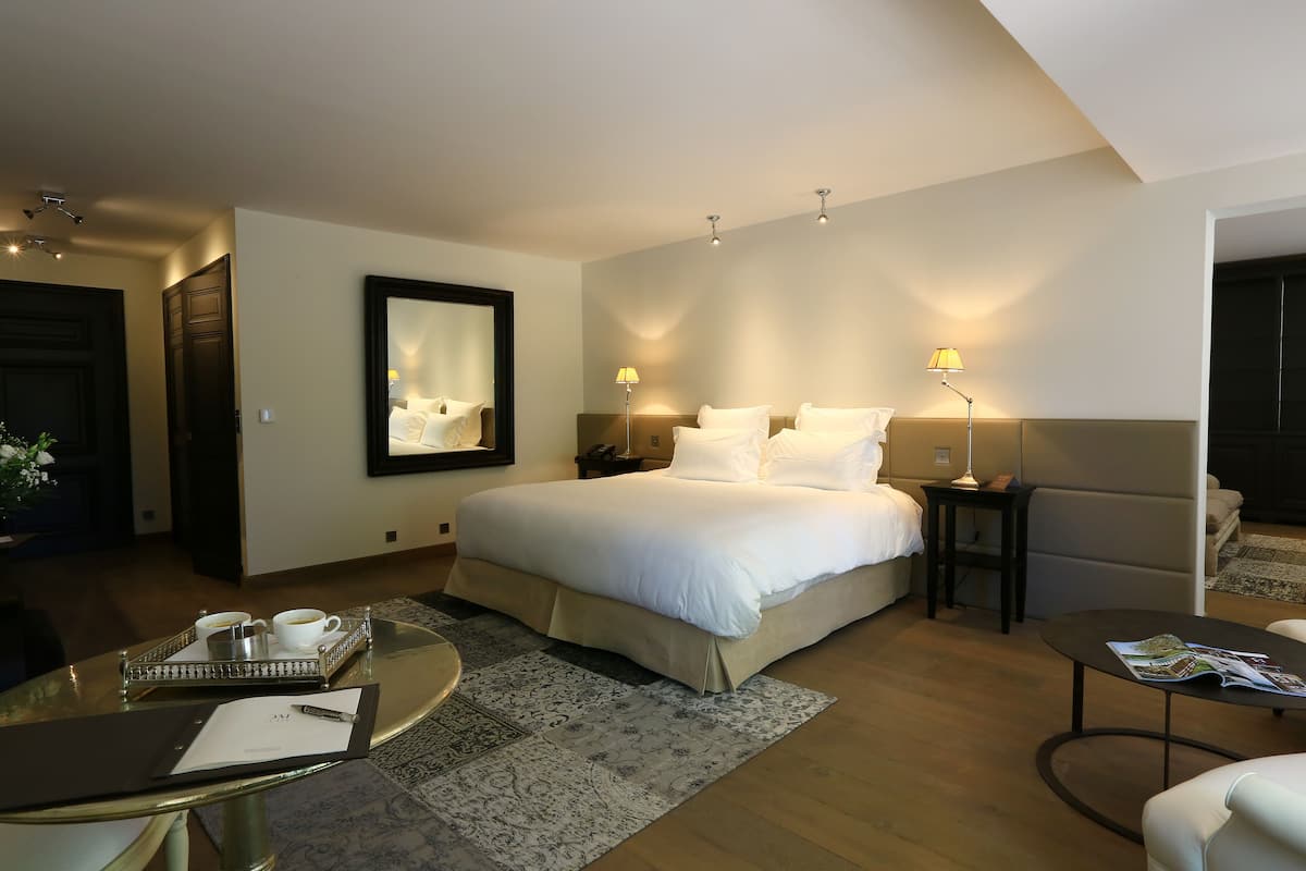 A hotel room with a large bed, bedside tables, a coffee table, and a seating area.