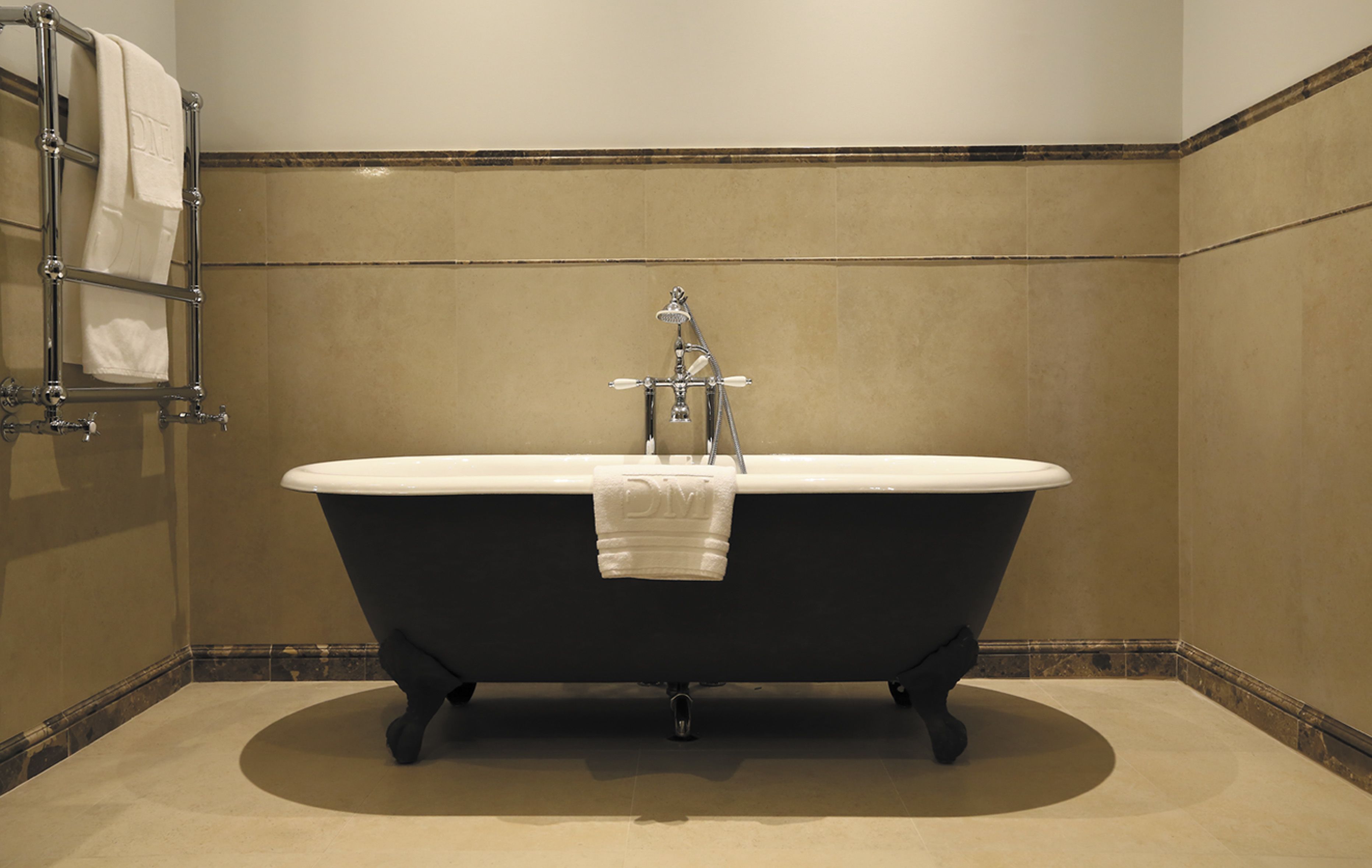 A bathroom with a freestanding bathtub, a towel rack, and a showerhead.