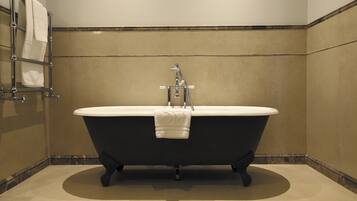 A bathroom with a freestanding bathtub, a towel rack, and a showerhead.